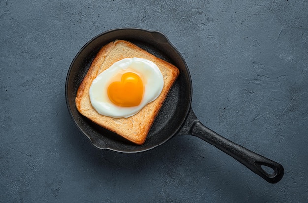 Huevos fritos con una yema en forma de corazón sobre pan tostado en un espacio de copia de vista superior de sartén