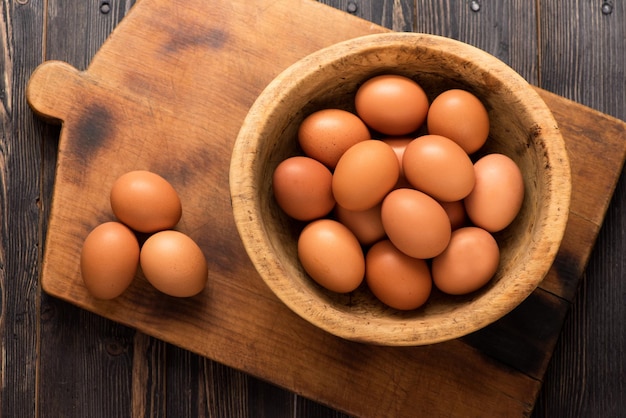 Huevos de gallina amarillos en un cuenco de madera sobre una vista superior de fondo de madera