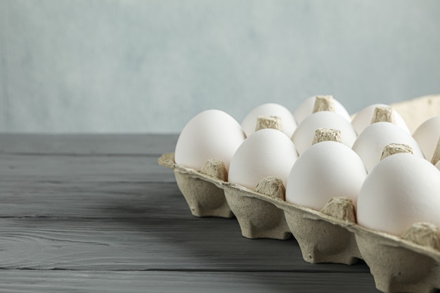 Huevos de gallina blanca en caja de cartón sobre mesa de madera