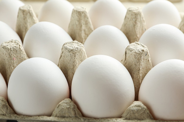 Huevos de gallina blanca en caja de cartón sobre mesa de madera