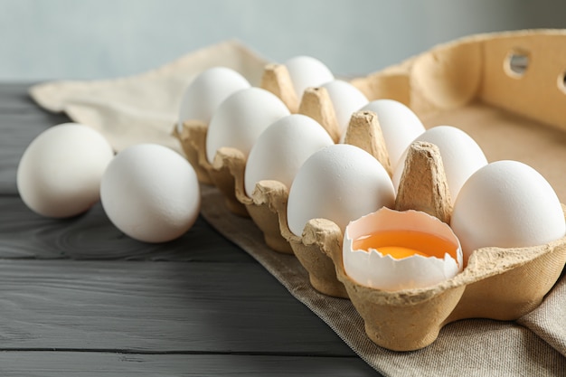 Huevos de gallina blanca en caja de cartón sobre mesa de madera