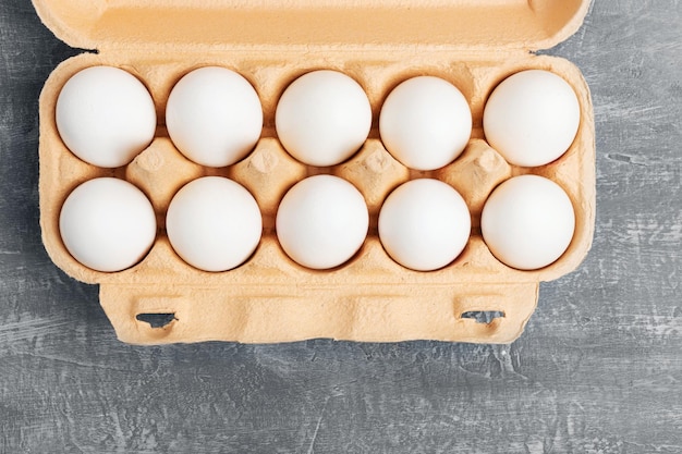 Huevos de gallina blanca en caja de cartón en la vista superior de fondo con textura gris