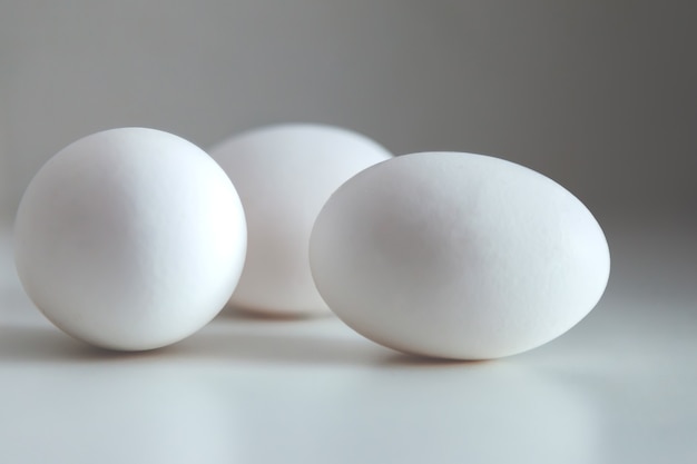 Huevos de gallina blanca sobre fondo blanco. Huevo en la mesa, comida sana natural. Fondo minimalista creativo. Concepto de agricultura ecológica y nutrición adecuada. Lugar para una inscripción o logotipo