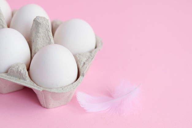 Huevos de gallina blanca sobre una superficie rosa