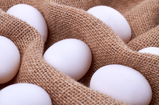 Huevos de gallina blanca sobre una tela de yute