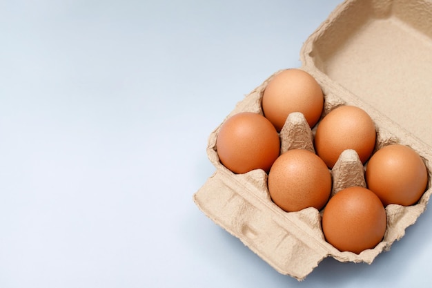 Huevos de gallina en una caja de cartón listos para cocinar en la mesa de la cocina