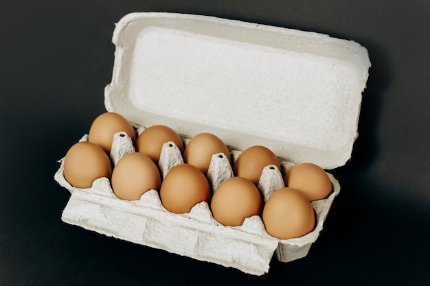 Huevos de gallina en una caja de papel gris sobre fondo negro