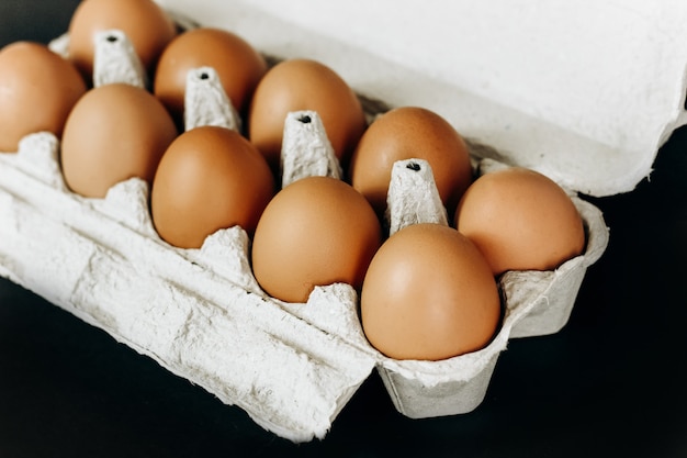 Huevos de gallina en una caja de papel gris sobre fondo negro