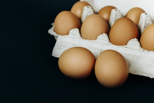 Huevos de gallina en una caja de papel gris sobre fondo negro