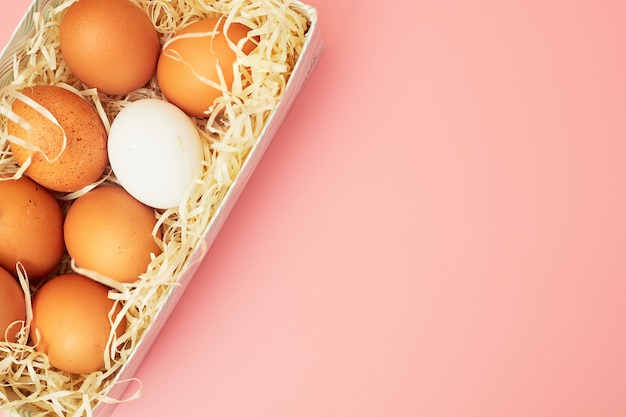 Foto huevos de gallina en una caja sobre un fondo rosa pastel, copias de espacio, flatlay