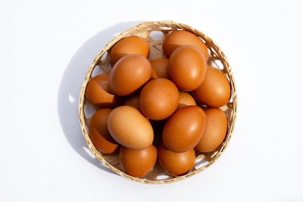 Huevos de gallina en canasta de bambú en blanco.