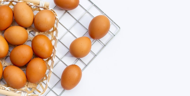 Huevos de gallina en canasta de bambú sobre blanco