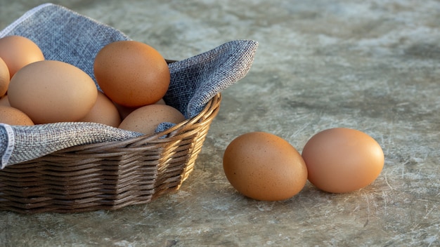 Huevos de gallina en una cesta sobre un fondo gris