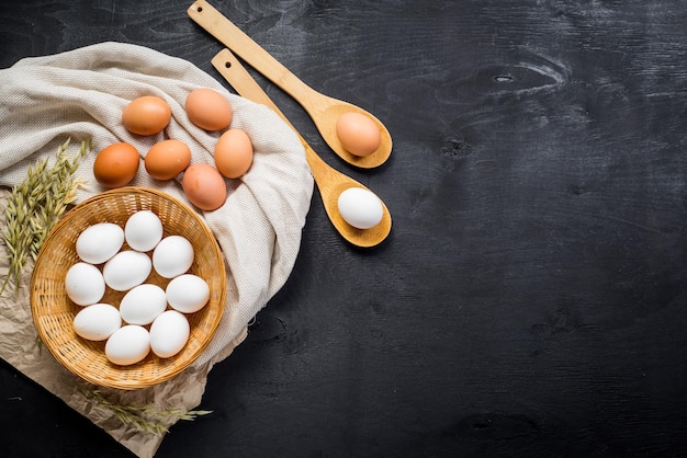 Huevos de gallina en la cesta sobre fondo de madera negra. copia espacio