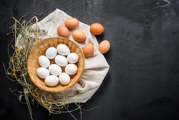 Huevos de gallina en la cesta sobre fondo de madera negra. copia espacio