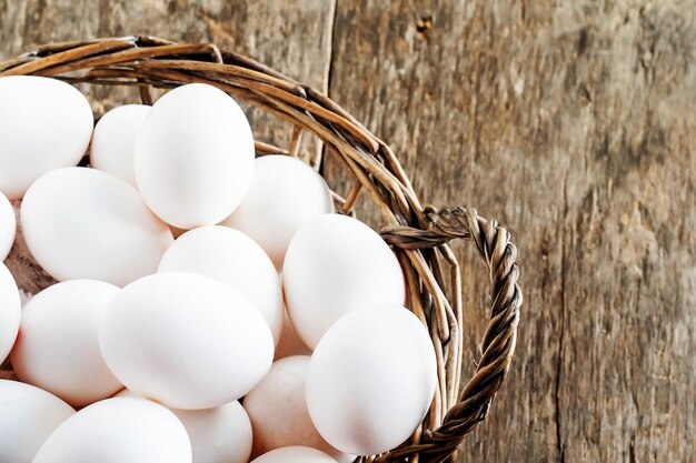 Huevos de gallina en la cesta sobre fondo de madera