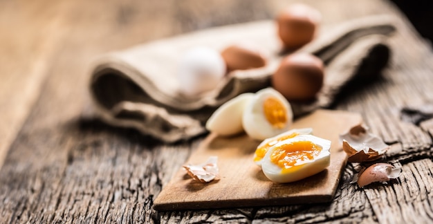 Huevos de gallina cocidos o crudos de primer plano sobre tabla de madera.