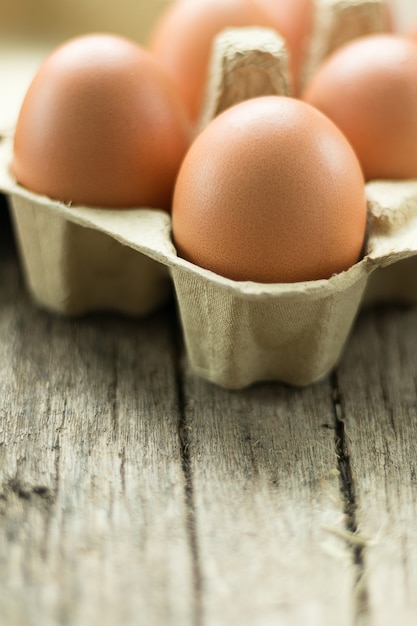 huevos de gallina cruda en caja de huevo sobre fondo de madera