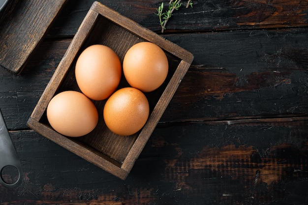 Huevos de gallina crudos en caja de huevos, sobre la vieja mesa de madera oscura.