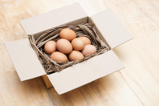 Foto huevos de gallina frescos en caja de papel sobre la mesa de madera