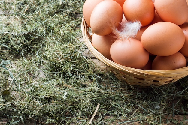 Huevos de gallina frescos en una cesta de paja en la granja. Estilo rústico