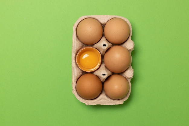 Huevos de gallina marrón fresca de Pascua en canasta ecológica y un huevo sobre fondo verde, plano, espacio de copia.