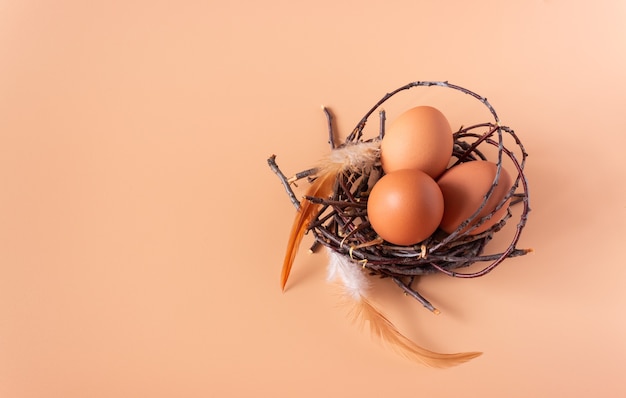 Huevos de gallina en un nido sobre una superficie beige.