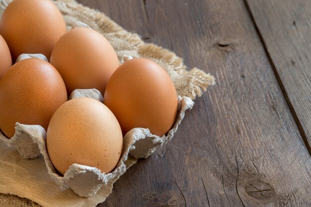 Huevos de gallina en el paquete de cerca en una mesa de madera