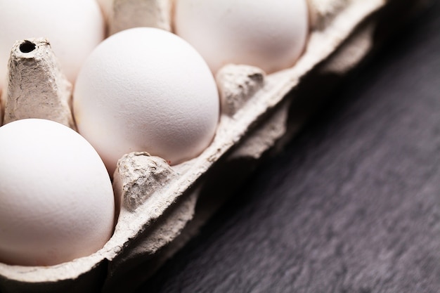 Huevos de gallina en un paquete sobre una mesa negra.