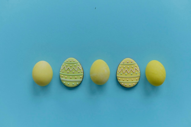 Huevos de gallina pintados de amarillo y huevos de galletas en un backgroung azul Vista superior