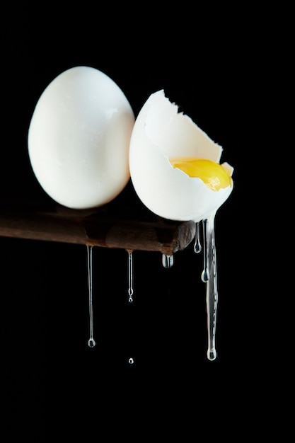 Huevos de gallina, se rompe un huevo en el que se ve la yema y la clara fluye hacia abajo