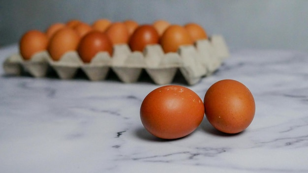 Huevos y huevos en cartón de huevos sobre mesa de mármol