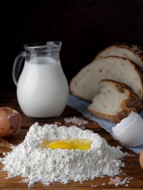 Huevos, leche y harina en la mesa de madera.