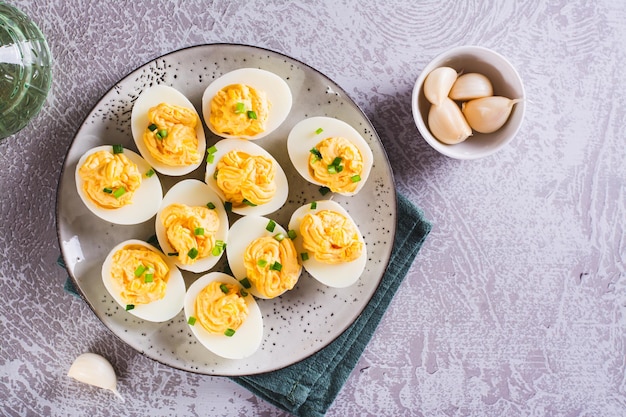 Foto huevos llenos de una mezcla de amarillo de queso, ajo y mayonesa en un plato, vista de arriba