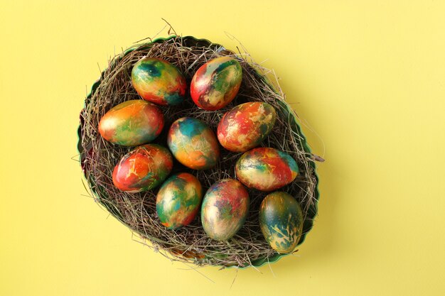 Huevos de mármol pintados con colorantes alimentarios para Pascua localizados sobre un fondo amarillo.