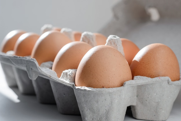 Huevos marrones en una bandeja de cartón a contraluz