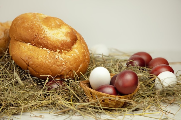 Huevos marrones y blancos y productos de panadería en heno sobre fondo blanco.