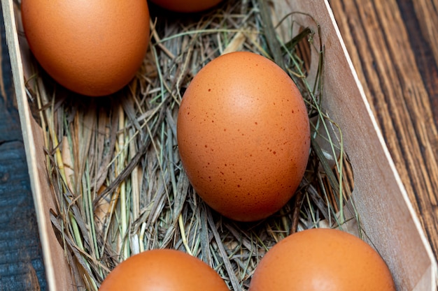 Huevos marrones de granja con paja en caja de corteza de abedul fondo de madera de cerca