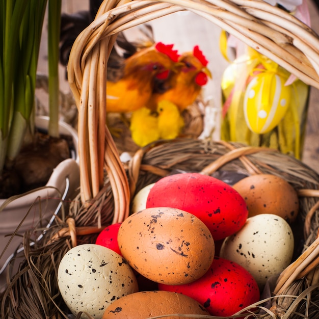 Huevos marrones, rojos y amarillos en canasta, decoración de Pascua