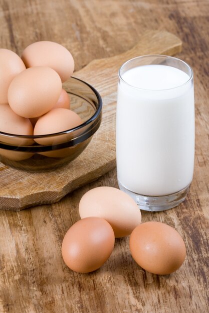 Foto huevos marrones y vaso de leche sobre fondo de madera