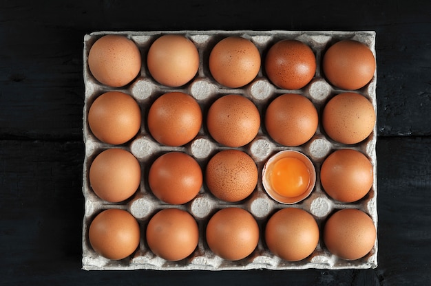 Huevos marrones y yema de huevo en caja de cartón