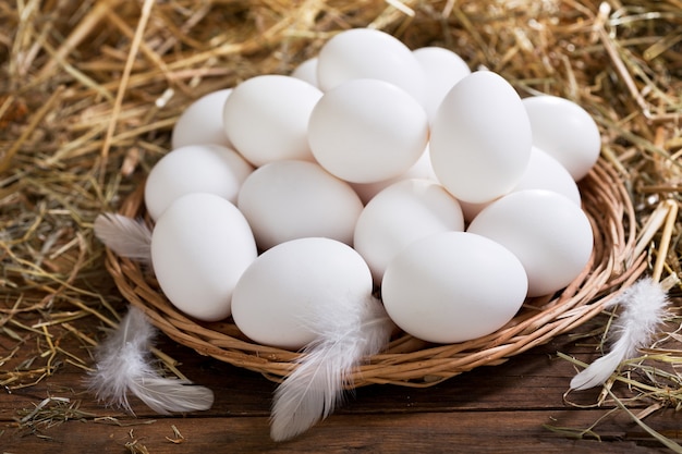 Huevos en un montón de heno sobre mesa de madera