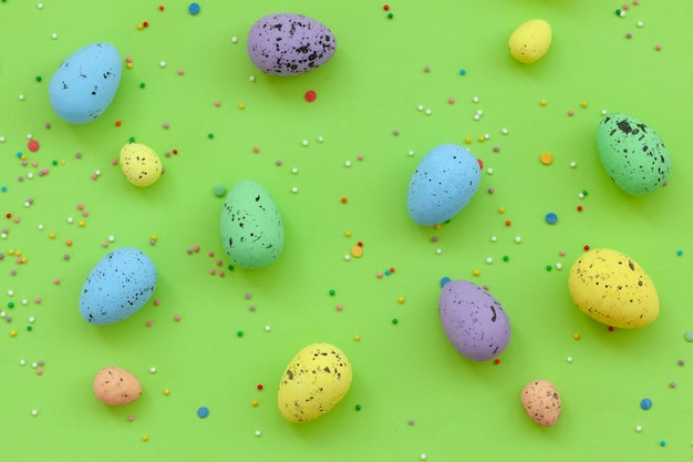 Huevos multicolores con confeti sobre fondo verde. Concepto de Pascua feliz.