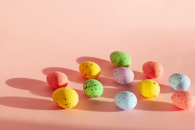 Huevos multicolores con luz solar por la mañana. Composiciones de colores sobre fondo rosa. Concepto de pascua.