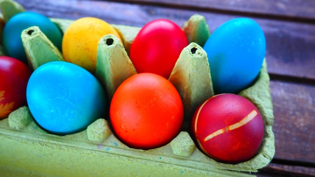 Huevos multicolores pintados con gouache y cáscara de cebolla en una caja de cartón sobre un fondo de mesa de madera Diez huevos cocidos Cartel postal para Semana Santa Vacaciones de Pascua Huevos marrones amarillos azules rojos
