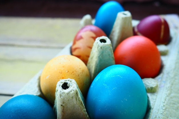 Foto huevos multicolores pintados con gouache y cáscara de cebolla en una caja de cartón sobre un fondo de mesa de madera diez huevos cocidos cartel postal para semana santa vacaciones de pascua huevos marrones amarillos azules rojos