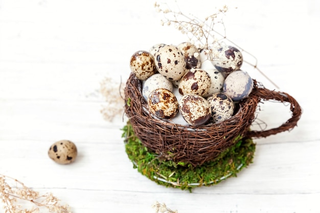 Huevos en nido taza sobre fondo blanco de madera