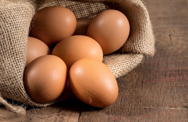 Huevos orgánicos recién puestos en sacos de arpillera en madera