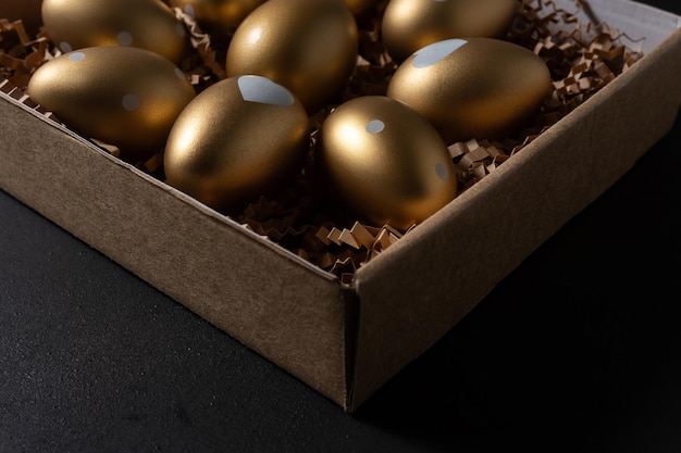 Foto huevos de oro en una caja de papel en una mesa oscura