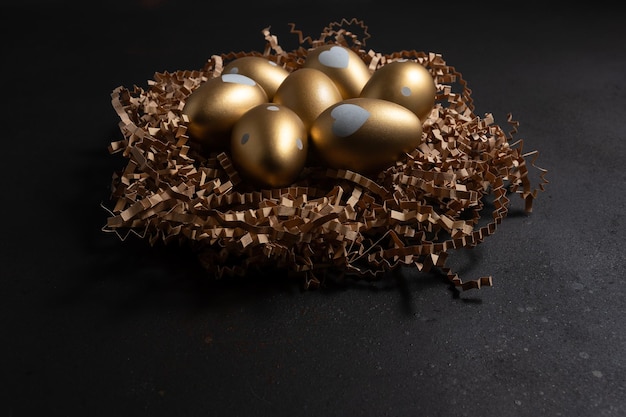 Foto huevos de oro en un nido de papel en una mesa oscura